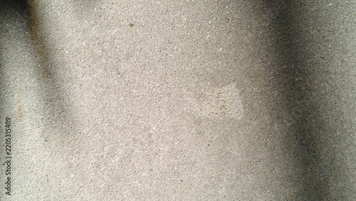 Grey concrete wall texture with natural sunlight shadows and copy space for commercial design