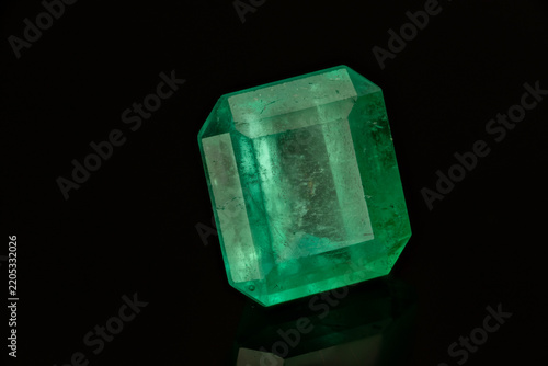 Colombian emerald cut green gemstone on dark background, macro close-up of loose precious stone
