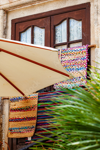 Old window, colorful rag rugs, parasol, and palm tree