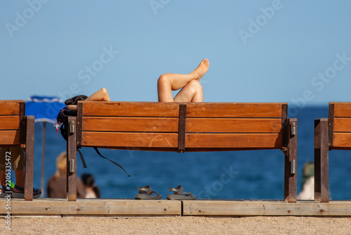 A moment of relaxation, legs crossed, on a bench facing the sea.
