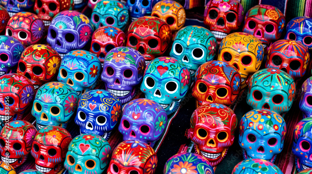 Fototapeta premium Colorful Mexican ceramic skulls decorated with vibrant floral patterns, representing traditional Día de los Muertos folk art, pottery and festive Day of the Dead celebration.