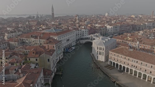 Aerial view of the Rialto Bridge spanning the Grand Canal in Venice, surrounded by historic terracotta-roofed buildings and narrow waterways in Venice, Veneto, Italy.