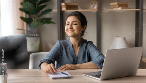 Relieved Woman After Solving a Problem. Indian woman sitting at a desk after successfully solving a difficult problem