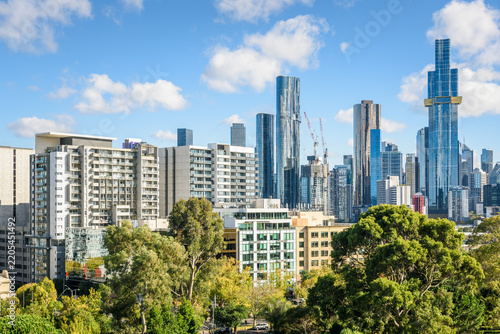 Modern apartment buildings along a tree lined street with glass office skyscrapers in background in Melbourne  city centre on a sunny autumn day