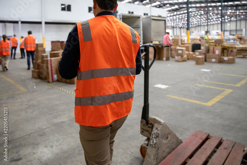 Warehouse Worker Wearing Safety Vest Moving Pallet