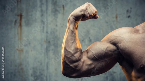 Muscular arm flexing against a textured wall background