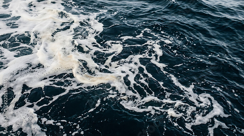 Abstract white sea foam swirling in dark blue ocean water with water texture
