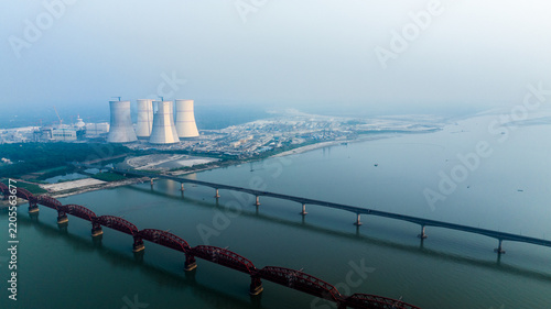 Aerial view of the Rooppur Nuclear Power Plant with cooling towers along the Padma River, featuring the historic Hardinge Bridge and Lalon Shah Bridge in Pabna, Rajshahi Division, Bangladesh.