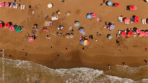 Aerial view of Alanya Incekum beach with colorful umbrellas, sunbathers relaxing on the sand, and gentle waves washing the shore in Alanya, Antalya, Turkiye.