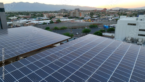 Aerial view of solar panels installed on a rooftop overlooking the city of Tucson with mountains in the background during sunrise in Tucson, Arizona, United States.