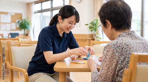 介護施設で折り紙を使ってレクレーションを行う日本人女性の介護士