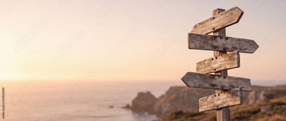 Obraz premium Blank wooden multi-directional signpost on a coastal cliff overlooking the ocean at sunset, symbolizing decision making, choices, travel directions, career paths, and future opportunities.