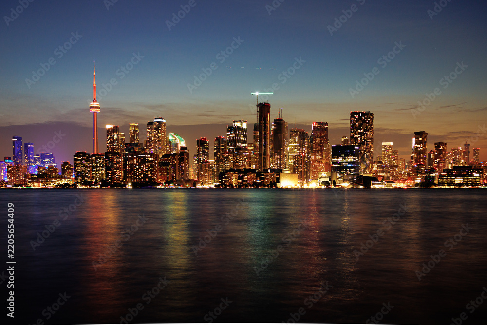 Obraz premium Toronto skyline at dusk with illuminated city lights reflecting on the water, vibrant urban night view. g.