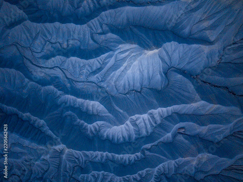 Aerial view of the intricate, eroded blue-toned badlands of Caineville, showcasing dramatic ridges and deep gullies carved into the desert landscape in Caineville, Utah, United States.