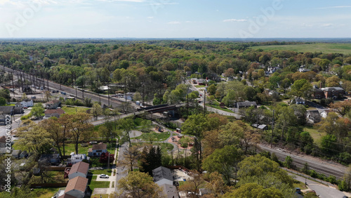Aerial view of the suburban landscape featuring a railway line crossing a bridge, residential houses, and a small park with playground equipment in Bowie, Maryland, United States.