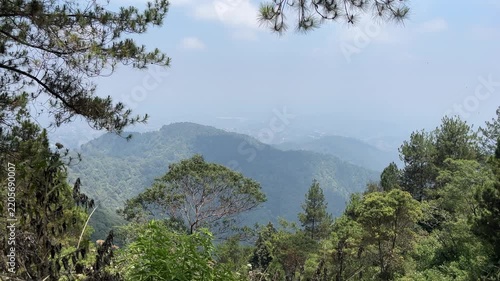 A scenic view of a valley in Tawangmangu, Central Java, Indonesia showing beautiful scenery, pine, trees. hills. blue sky, clouds. eco, ecology, environment. day. sunlight, sunshine, sunrise. bright. 