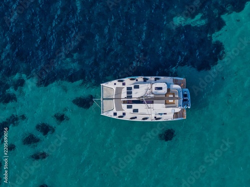 Aerial view of a white catamaran anchored in the clear turquoise waters near Ile Sainte-Marguerite in Cannes, Provence-Alpes-Cote d'Azur, France.
