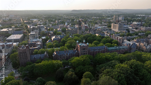 Aerial view of the historic Yale University campus featuring Gothic architecture, stone buildings, lush green trees, and surrounding urban streets in New Haven, Connecticut, United States.