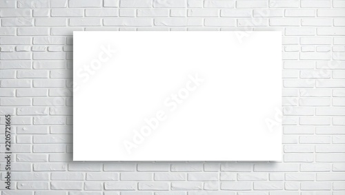 Blank white canvas frame hanging on a clean rustic white brick wall