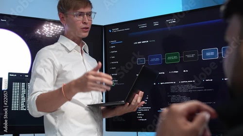 Engineer shows AI workflow on screens with colleague