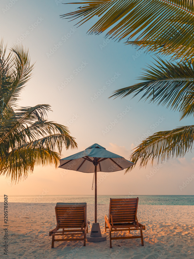 Obraz premium Romantic sunset tropical beach two loungers umbrella palm trees calm sea sandy shore glowing evening paradise. Perfect summer vacation travel scene. Luxury honeymoon couples relax love coastal getaway