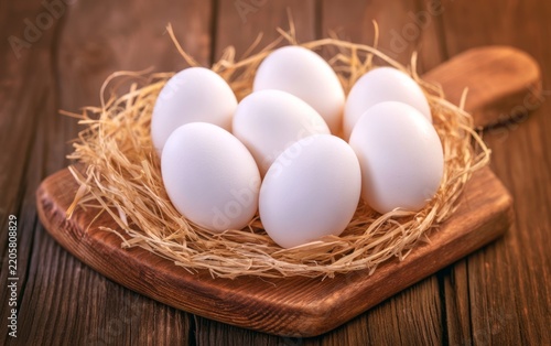 Fresh White Eggs Nestled in Straw Arrangement on Wooden Board for Farm Fresh Concept