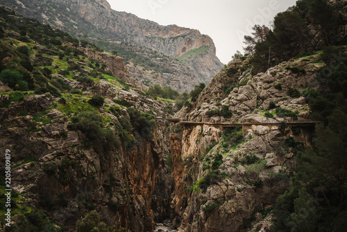 Deep narrow gorge with rushing river beneath a distant boardwalk at Caminito del Rey