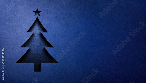 A stylized 3D Christmas tree emblem, cut from a blue-painted concrete surface, featuring crisp edges, subtle shading, and a rough texture.