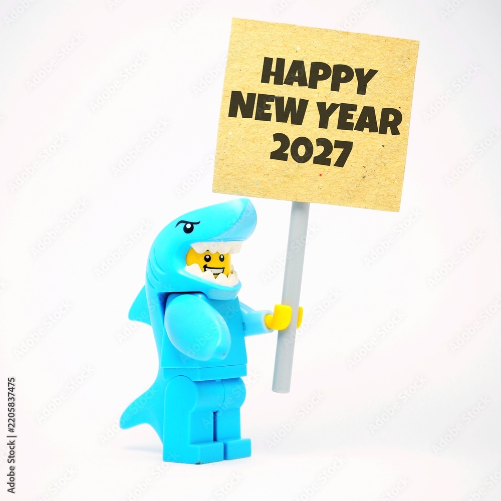 Obraz premium Indonesia - June 12, 2026 : Mini toy of action figure at table with blur background. Miniature photography concept design. Minifigure of Shark Character with HAPPY NEW YEAR 2027 text at poster banner.