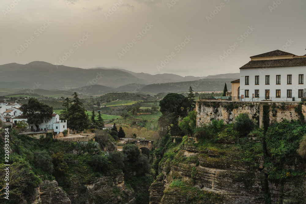 Fototapeta premium Green Tajo gorge and valley with whitewashed houses and hazy mountains in Ronda, Spain