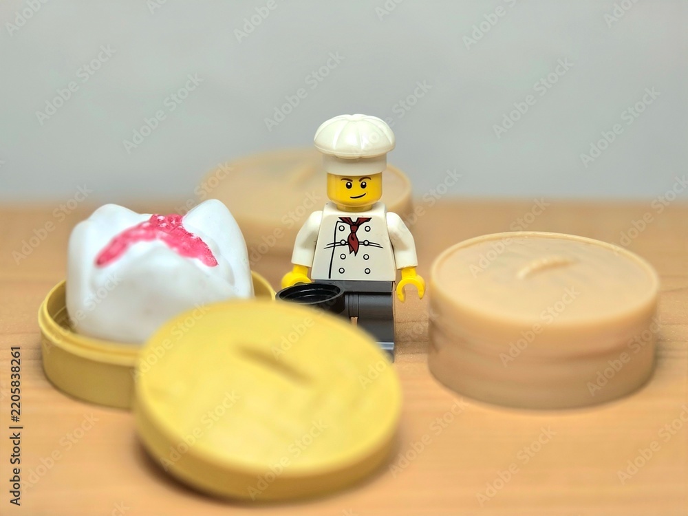 Obraz premium Indonesia - September 26, 2026 : Mini toy of action figure at table with blur background. Miniature photography concept design. Minifigure of chef character with khinkali dumpling squishy at kitchen.