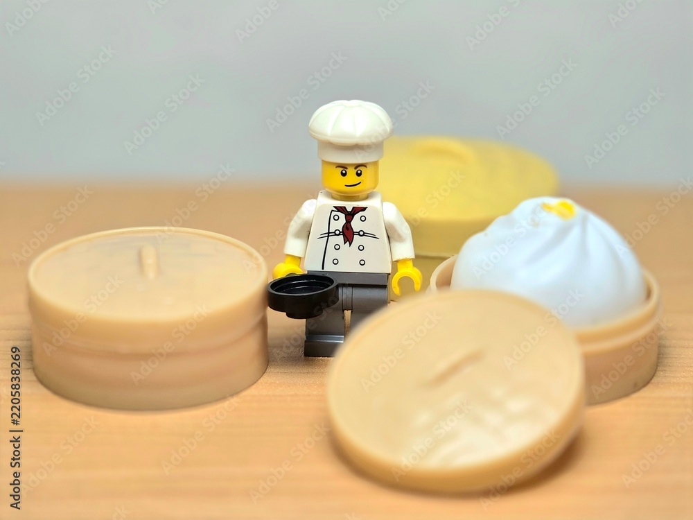 Obraz premium Indonesia - September 26, 2026 : Mini toy of action figure at table with blur background. Miniature photography concept design. Minifigure of chef character with khinkali dumpling squishy at kitchen.