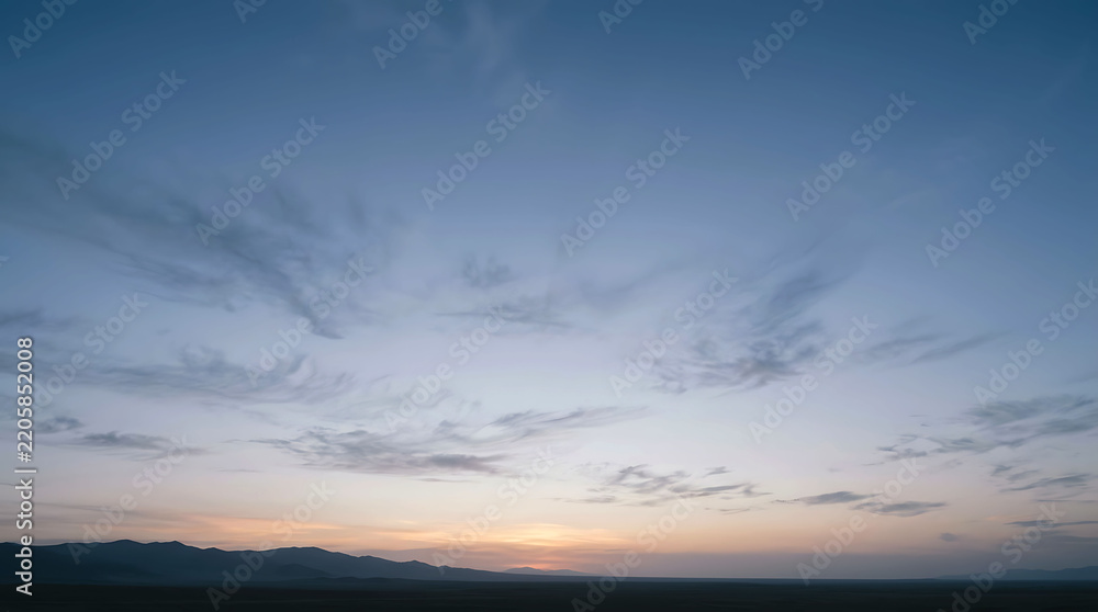 Fototapeta premium Serene sunset sky with wispy clouds over distant mountain range on the horizon