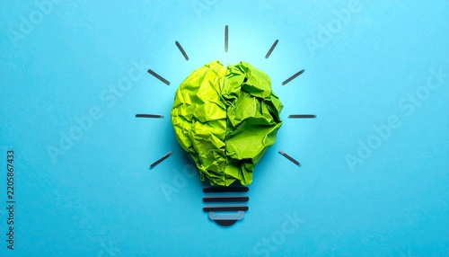 A light bulb shape made from crumpled green paper, representing an eco-friendly idea or sustainable energy concept on sky blue background 
3