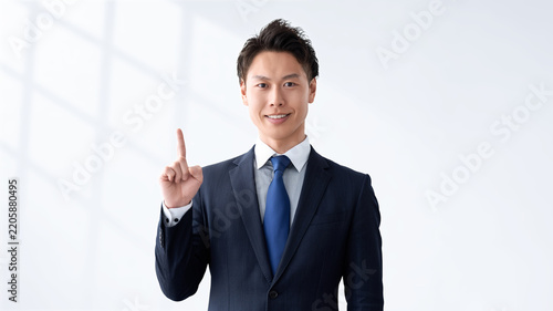 人差し指を立てて案内する男性ビジネスマン