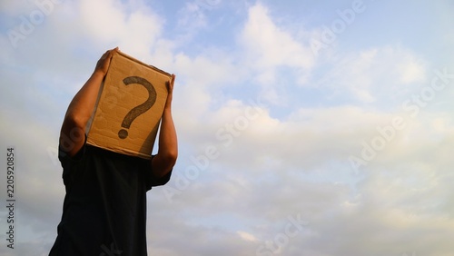 Person holding a cardboard box with a question mark over their head against a cloudy sky.