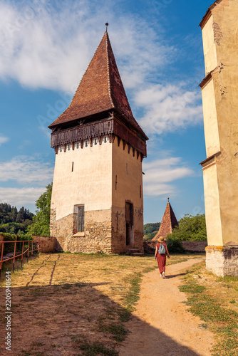Woman walking beside historic defensive tower at Biertan fortified church in Romania