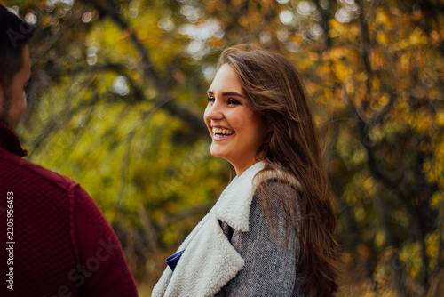 Smiling woman enjoying conversation in autumn park.