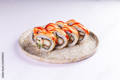 Tempura shrimp sushi rolls with spicy sauce on ceramic plate culinary