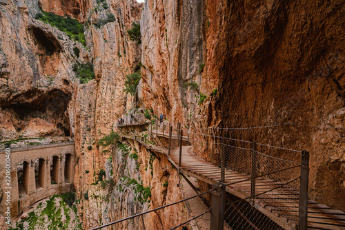 Cliffside boardwalk trail winding past a stone viaduct at Caminito del Rey, Spain