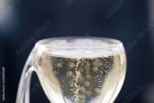 Close-up macro view of golden sparkling champagne with effervescent bubbles rising inside a clear glass against a dark background