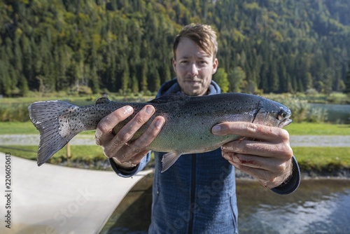 Man holding caught trout, fishing