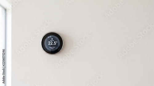 Smart home thermostat displaying current heating temperature and target setting on modern residential wall for energy management and comfortable living space