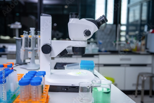 Modern laboratory workspace featuring a high-resolution microscope, colorful test tubes, glassware, and a green plant sample for scientific research and biotechnology.