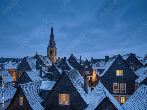 Snow Covered Village Rooftops with Church Spire at Twilight in Winter