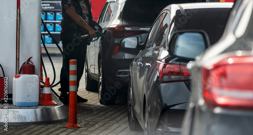 Fuel station worker fills car at pump