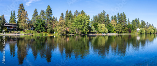 Mirror Pond on the Deschutes River in Bend Oregon reflects evergreen trees and homes along its shoreline.