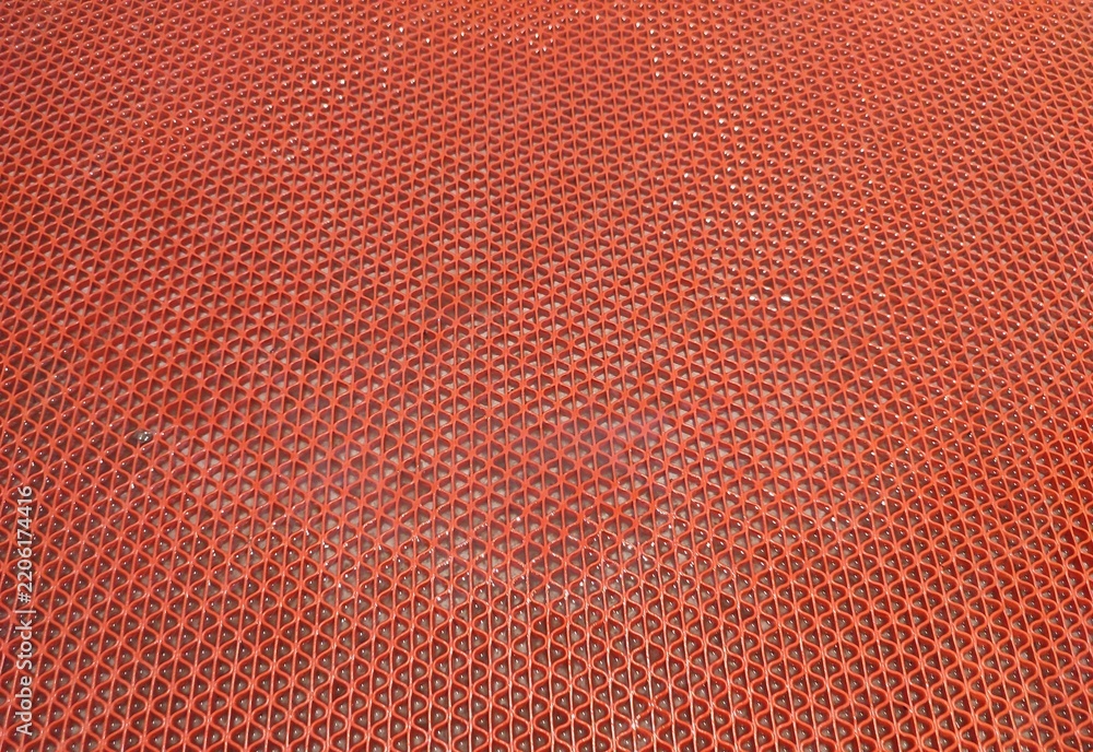 Obraz premium A wet orange anti-slip plastic mat or hollow mesh rubber carpet, featuring water droplets and a repeating geometric pattern
