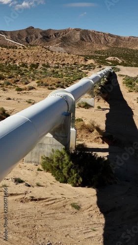 Aerial shot of the Los Angeles Aqueduct as it passes over some low mountains in California. The aqueduct supplies water to Los Angeles and Southern California. Vertical video.