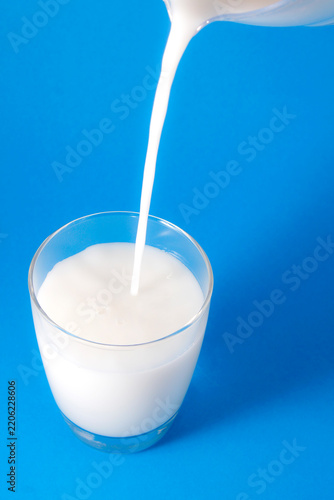 Fresh Milk Pouring into Glass on Bright Blue Background